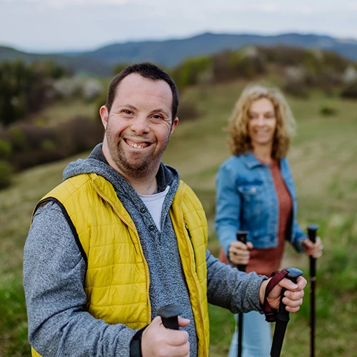 Portrait of happy young man with Down syndrome with his mother hiking together in nature.