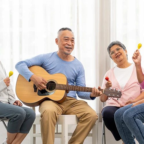 Group of senior peoples enjoy playing guitar and singing together in living room 